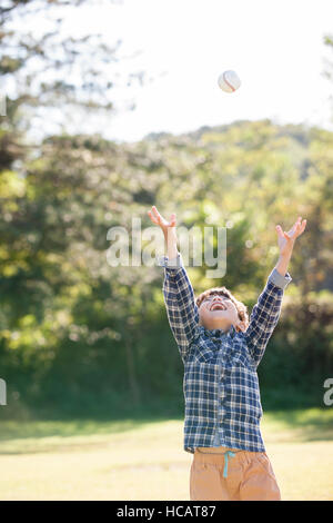 Five-Year-Old koreanischen Boy für einen Baseball auf Grünland zu erreichen Stockfoto