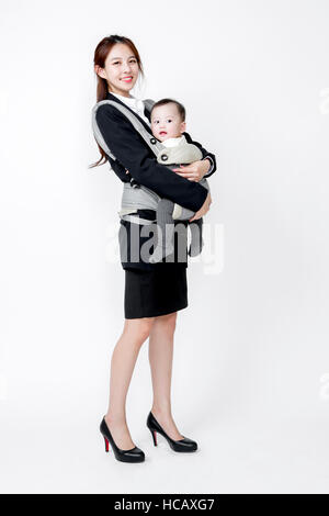 Seitenansicht des lächelnden Geschäftsfrau hält ihr Baby in einem Träger Stockfoto