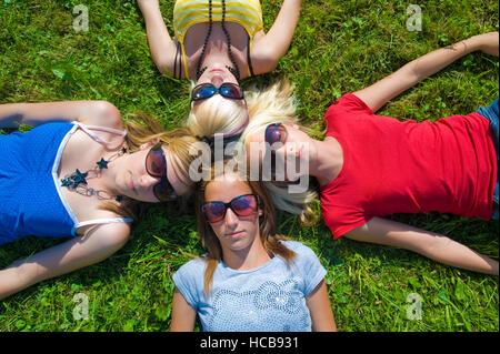 Symbolisches Bild für Freundeskreis, Teenager, die Kopf an Kopf auf einer Wiese liegend Stockfoto