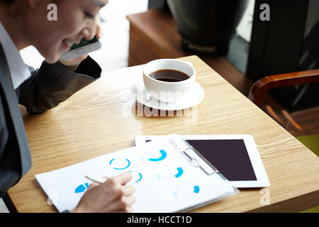 Seitenansicht des jungen lächelnd Geschäftsfrau mit Papieren im café Stockfoto