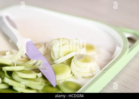 In Scheiben geschnittenen Porree auf Schneidebrett. Huhn, Käse und Lauch-Paket-Serie zu machen. Stockfoto