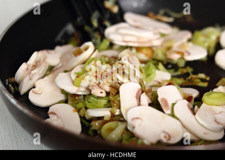 Rohe Pilze Scheiben und gebratenem Lauch in der Pfanne. Huhn, Käse und Lauch-Paket-Serie zu machen. Stockfoto