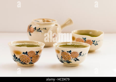 Japanische Tee mit Chrysanthemen Dekoration aufgestellt. Tasse mit Kaffee, Schüssel grünem Tee und Kaffee-Pott auf normales Licht Oberfläche. Stockfoto