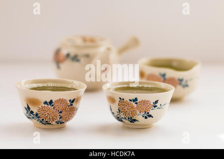 Japanische Tee mit Chrysanthemen Dekoration aufgestellt. Tassen für Tee, Schüssel grünem Tee und Kaffee-Pott auf normales Licht Oberfläche. Flache konzentrieren. Stockfoto