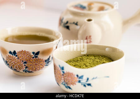 Japanische Tee mit Chrysanthemen Dekoration aufgestellt. Tasse mit Kaffee, Schüssel grünem Tee und Kaffee-Pott auf normales Licht Oberfläche. Flache konzentrieren. Stockfoto