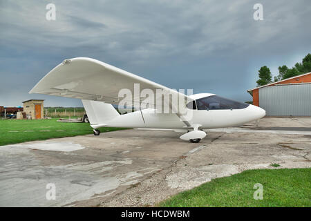 Kiew, Ukraine - 19. Juli 2014: Leichten zweimotorigen Privatflugzeug auf einen Flugplatz mit stürmischen Himmel und Hangar auf dem Hintergrund geparkt Stockfoto