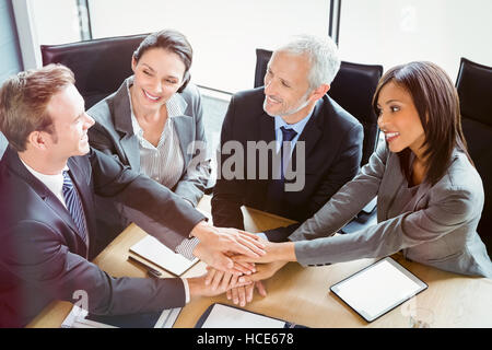 Erhöhte Ansicht von Geschäftsleuten, die Hände im Konferenzraum stapeln Stockfoto