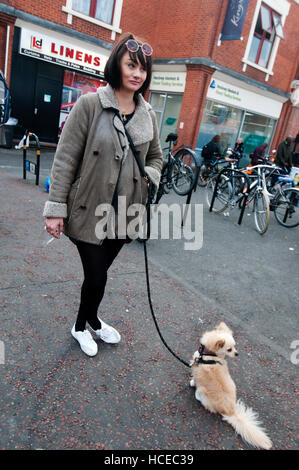 Hackney. Ridley Straße Markt. Frau mit kleine Hund wartete, Rauchen. Stockfoto