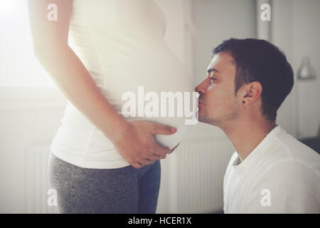 Mann küssen Neugeborenen durch Frau Bauch Stockfoto