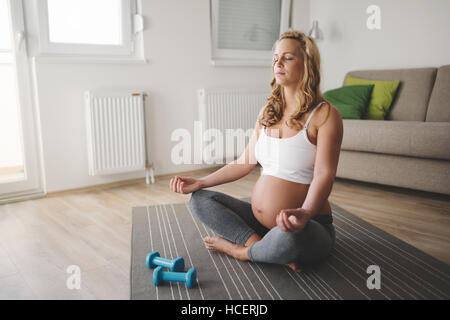 Schöne schwangere Frau zu Hause meditieren Stockfoto