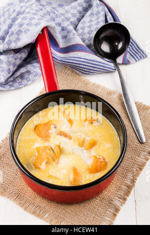 frisch zubereitete traditionelle schottische Fischsuppe, Cullen Skink, in einem roten Emaille-Topf mit Kelle auf jute Stockfoto