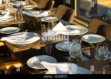 Tisch im Restaurant serviert für mehrere Personen mit dunklen Stühle, Teller, Gläser, Gabeln Stockfoto