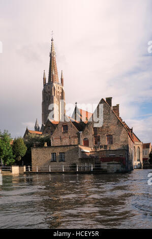 Sint-Janshospitaal, Saint John's Hospital, Brügge. Im 12. Jahrhundert, gesehen aus dem Kanal mit dem Turm der Onze-Lieve-Vrouwekerk oder Kirche begonnen Stockfoto