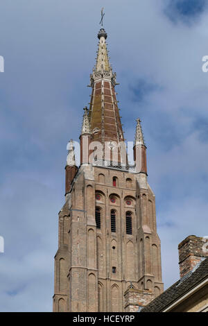 Onze-Lieve-Vrouwekerk oder Frauenkirche, Brügge, Belgien. Turm aus rotem Backstein auf braune Backsteinturm mit Stein Kreuzblumen Stockfoto