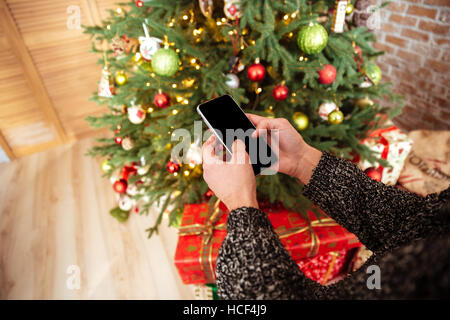 Zugeschnittenes Bild des Mannes mit Telefon in der Nähe der Tannenbaum Stockfoto