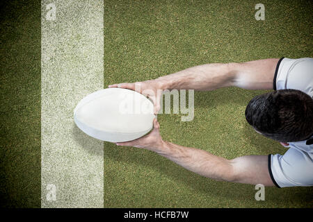 Zusammengesetztes Bild der Vogelperspektive Ansicht der Mann, der Rugby-Ball mit beiden Händen hält Stockfoto