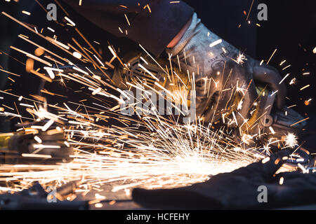 Winkelschleifer. Ein Mann arbeitet mit elektrischen Schleifer-Werkzeug auf ein Metallteil Funken fliegen überall. Stockfoto