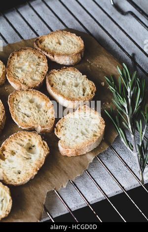 Geröstetes Baguette Brot auf Backpapier auf Kuchengitter Stockfoto