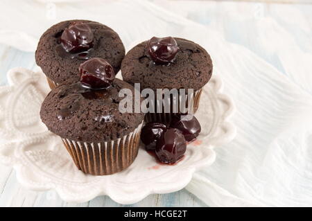 Dunkle Schokoladen-Muffins in Pappbecher auf einem Teller Stockfoto