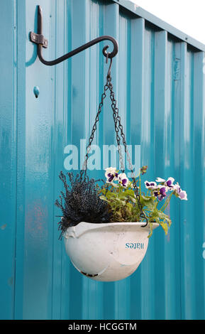 Eine alte Schutzhelm Baumeister in eine Blumenampel schmücken das Horten rund um eine Baustelle Wates umgewandelt Stockfoto