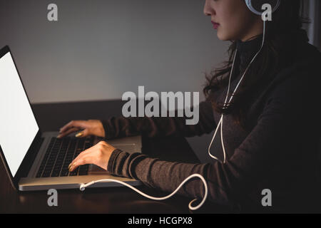 Frau Kopfhörer anhören, während mit laptop Stockfoto