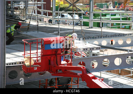 PPE ausgestattete Bauarbeiter im Cherry Picker Einbau PCC precast Planken in kronenmutter Stahl Rahmen auf dem neuen Parkplatz Bauvorhaben Bolton GROSSBRITANNIEN Stockfoto