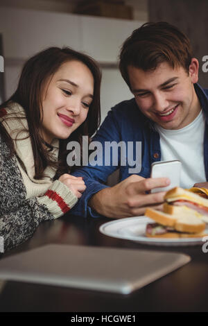 Paar mit Handy beim Frühstück Stockfoto