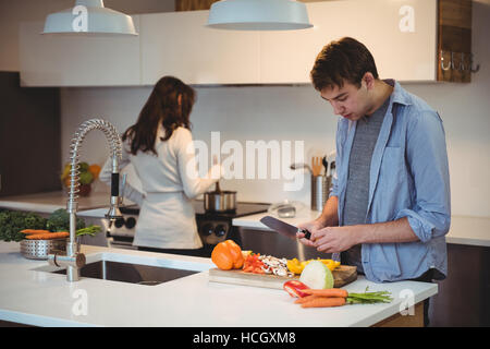 Zerkleinern von Gemüse in der Küche beim Kochen im Hintergrund Frau Mann Stockfoto