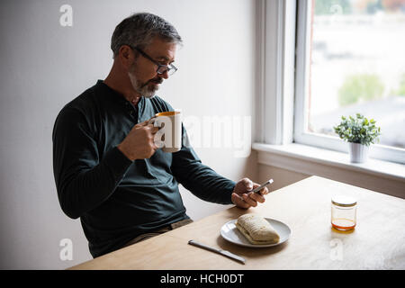 Mann mit Handy bei einer Tasse Kaffee Stockfoto