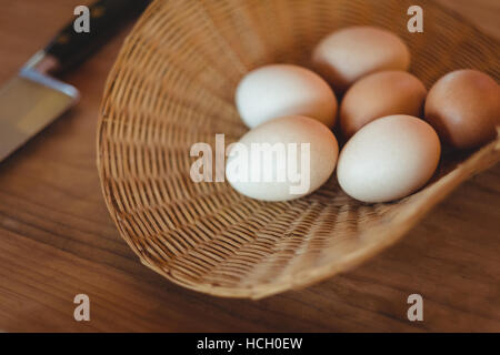 Eiern in Weidenkorb auf Holztisch Stockfoto