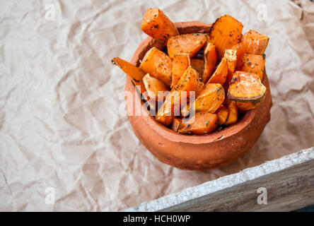 Gebackene Süßkartoffel mit Kräutern der Provence in einem Topf auf einem hölzernen Hintergrund Scheiben. Perfekt für die Detox-Diät oder einfach nur eine gesunde Mahlzeit. Stockfoto