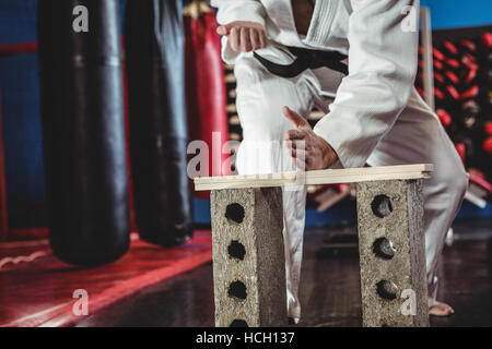 Karate Spieler brechen Holzbrett Stockfoto