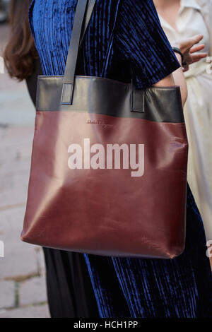 Frau mit Ferragamo Ledertasche und blauen Samtkleid vor Salvatore Ferragamo Modenschau, Milan Fashion Week Streetstyle. Stockfoto