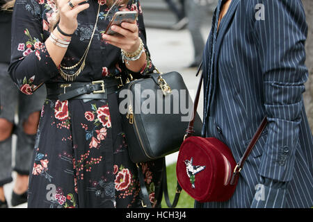 Frau mit floralen schwarzen Kleid und roten Samtbeutel vor Giorgio Armani Fashion Show in Mailand Fashion Week Streetstyle in Mailand. Stockfoto