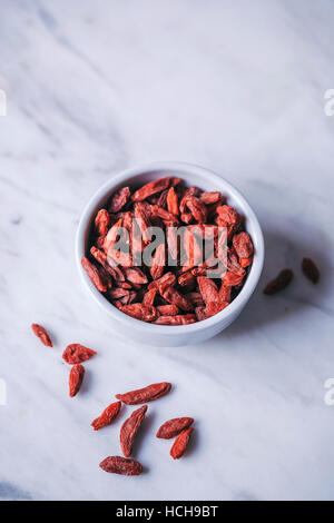 Goji-Beeren in einer kleinen Schüssel weiß und weißer Marmor-Tisch Stockfoto