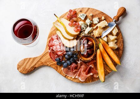 Fleisch und Käse Teller Antipasti snack mit Schinken, Parmesan, blaue Käse, Cantaloupe-Melone und Oliven auf Olivenholz serviert Board auf Beton Stockfoto