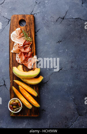 Fleisch Teller Antipasti-snack mit Prosciutto-Schinken, Melone Melone und Oliven auf dunklem Stein Textfreiraum Stockfoto