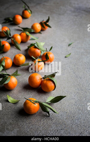 Frische Mandarinen mit grünen Blättern auf grauem Hintergrund Stockfoto