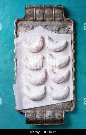 Hausgemachte Weihnachten Muttern Cookies Halbmond mit Zuckerpuder auf Vintage Metalltablett mit Backpapier als Tanne über Türkis bewaldet Textur Zeitmessung Stockfoto