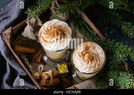 Kürbis würzig Latte mit Sahne und Zimt in zwei Gläser im Holzbrett mit Textil- und Dekoration und Tanne Weihnachtsbaum andere stehen Stockfoto