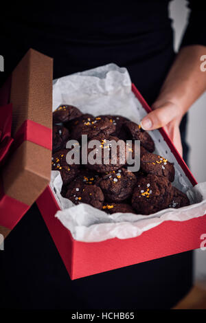 Eine Frau hält eine Geschenk-Box voller Zitrusfrüchte Schokoladenkekse. Stockfoto