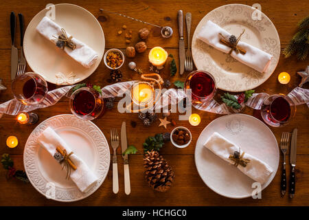 Weihnachten Tischdekoration für Familienessen an einem gemütlichen rustikalen Tisch mit Kerzen und Dekorationen. Ansicht von oben. Stockfoto