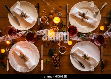 Weihnachten Tischdekoration für Familienessen an einem gemütlichen rustikalen Tisch mit Kerzen und Dekorationen. Ansicht von oben. Stockfoto