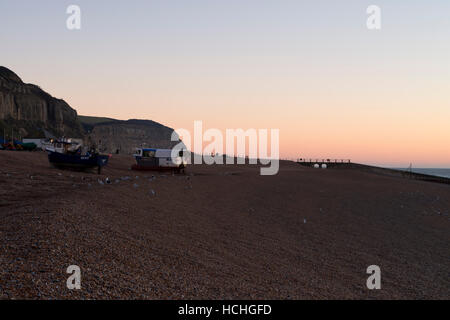 Blick auf Osthügel und Angelboote/Fischerboote am Strand bei Sonnenaufgang in Hastings Stockfoto