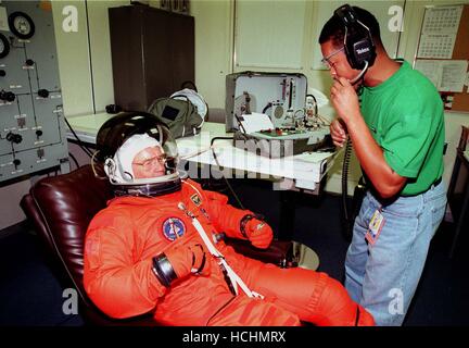 STS-95 Nutzlast-Spezialist John H. Glenn Jr., US-Senator aus Ohio und einer der ursprünglichen sieben Projekt Mercury Astronauten, passt sich mit Hilfe von George Brittingham, United Space Alliance in den Betrieb und die Kasse (O & C) Gebäude vor seiner Reise nach Startrampe 39-B am 9. Oktober 1998. Glenn und der Rest der Crew von STS-95 sind am KSC in Terminal Countdown Demonstration Test (TCDT) teilnehmen, die Einarbeitung Missionsarbeit, Fluchtwege Training und eine simulierte Hauptmaschine cutoff enthält. Im Anschluss an die TCDT wird die Crew nach Houston für Finale zurückkehren Stockfoto