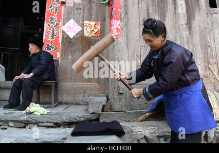 Rongjiang, Chinas Provinz Guizhou. 8. Dezember 2016. Ein Dorfbewohner schlägt Drapierung zu Hause in Dali Dong Lager von Rongjiang County, Südwesten Chinas Provinz Guizhou, 8. Dezember 2016. Alten Gebäude in Dali Dong Camp, die alle mit Holzkonstruktionen der Zapfen- und verzapfen bestehen, wurden als wichtige Kulturdenkmal Einheit unter Staatsschutz 2013 aufgelistet. © Lu Bo'an/Xinhua/Alamy Live-Nachrichten Stockfoto