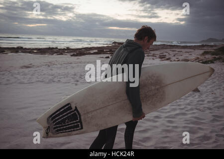 Mann mit Surfbrett zu Fuß am Strand Stockfoto