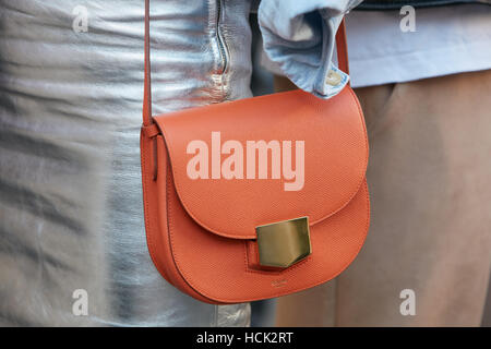 Frau mit Celine orange Tasche und Silber Rock vor Salvatore Ferragamo Modenschau, Milan Fashion Week Streetstyle in Mailand Stockfoto