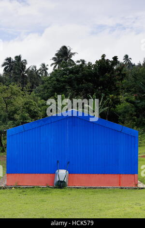 Aluminium-Schubkarre stützte sich auf die blaue Zinn Wand eines Pavillons im Topol Mittelschule Komplex der Newa Dorf in der Nähe von Olal Dorf an der Nor Stockfoto