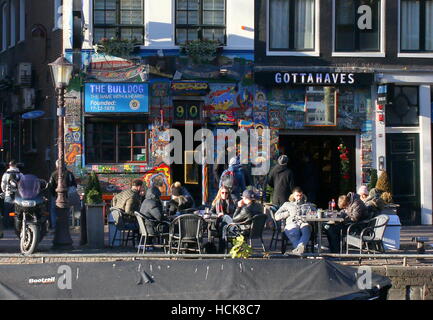 Personen auf Terrasse vor Coffeeshop Bulldog am Oudezijds Voorburgwal Kanal, Amsterdam, Niederlande Stockfoto